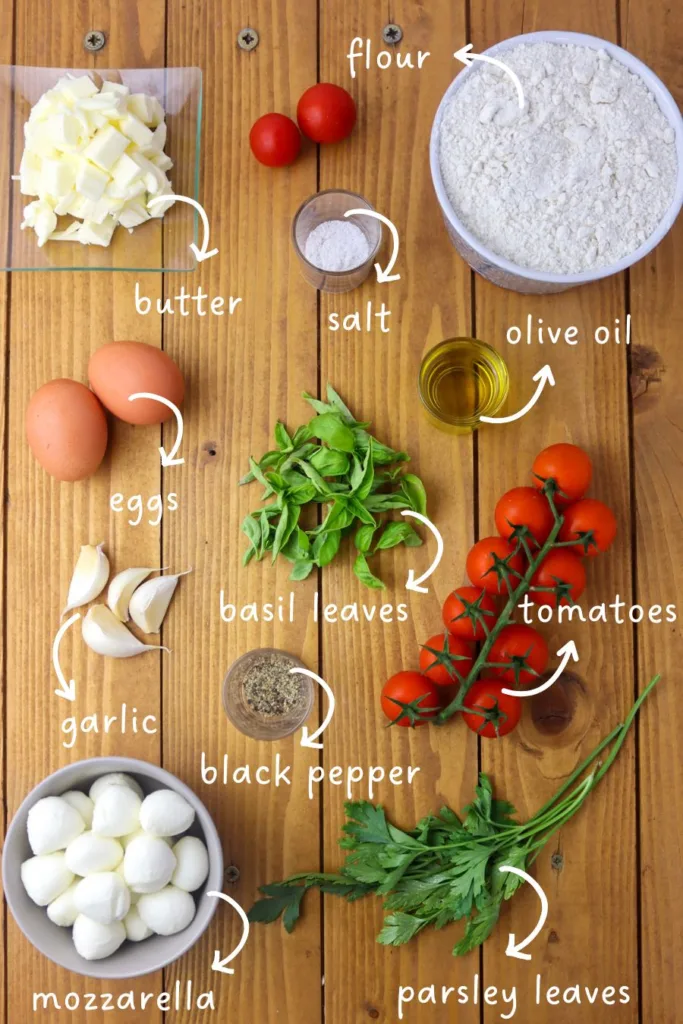 gathering ingredients for caprese empanadas: flour, butter, tomato, mozzarella, basil, eggs, olive oil, garlic, salt, black pepper