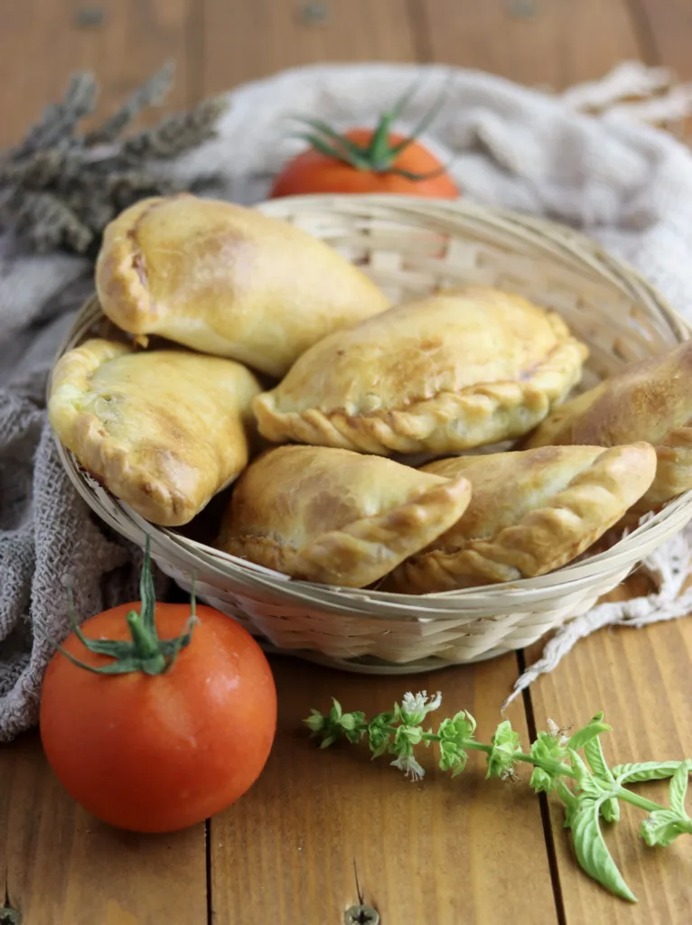 image showing bread basket ful of fresh and hot caprese empanadas with basil flowers