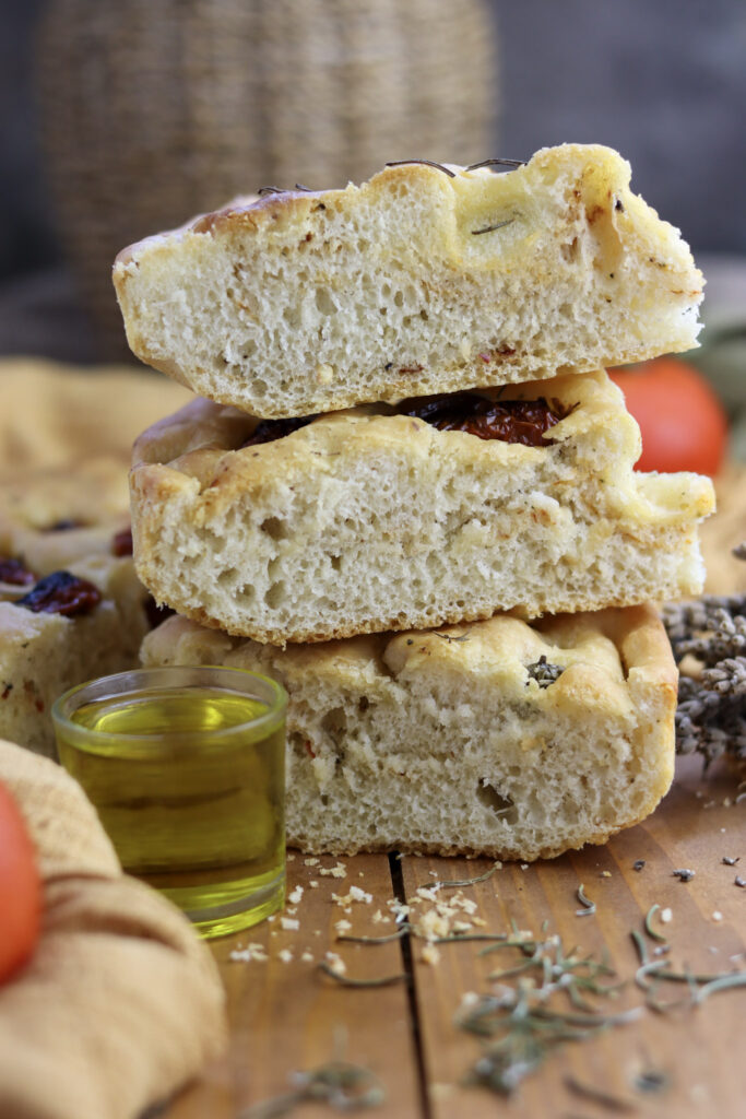 three pieces of freshly baked focaccia and a glass of olive oil 