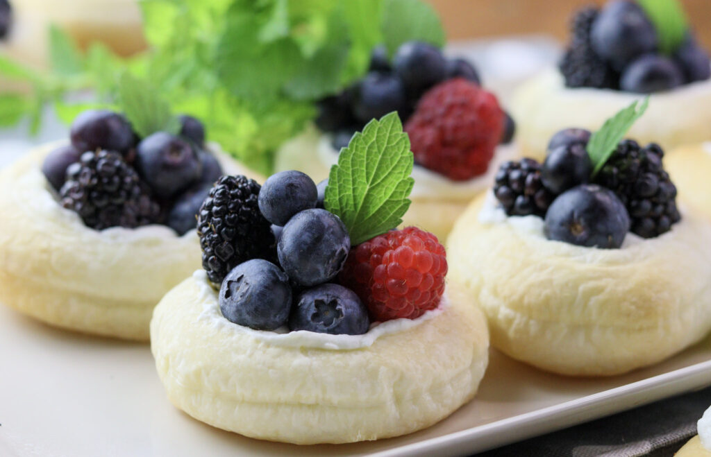 image of fruit tarts with puff pastry served on a plate with lemon balm leaves 