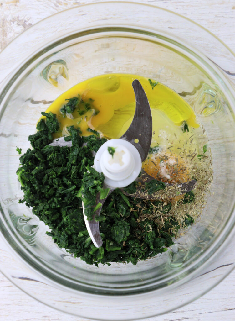 image showing ingredients for green pasta in a blender: blanched wild garlic, eggs, olive oil, salt and thyme