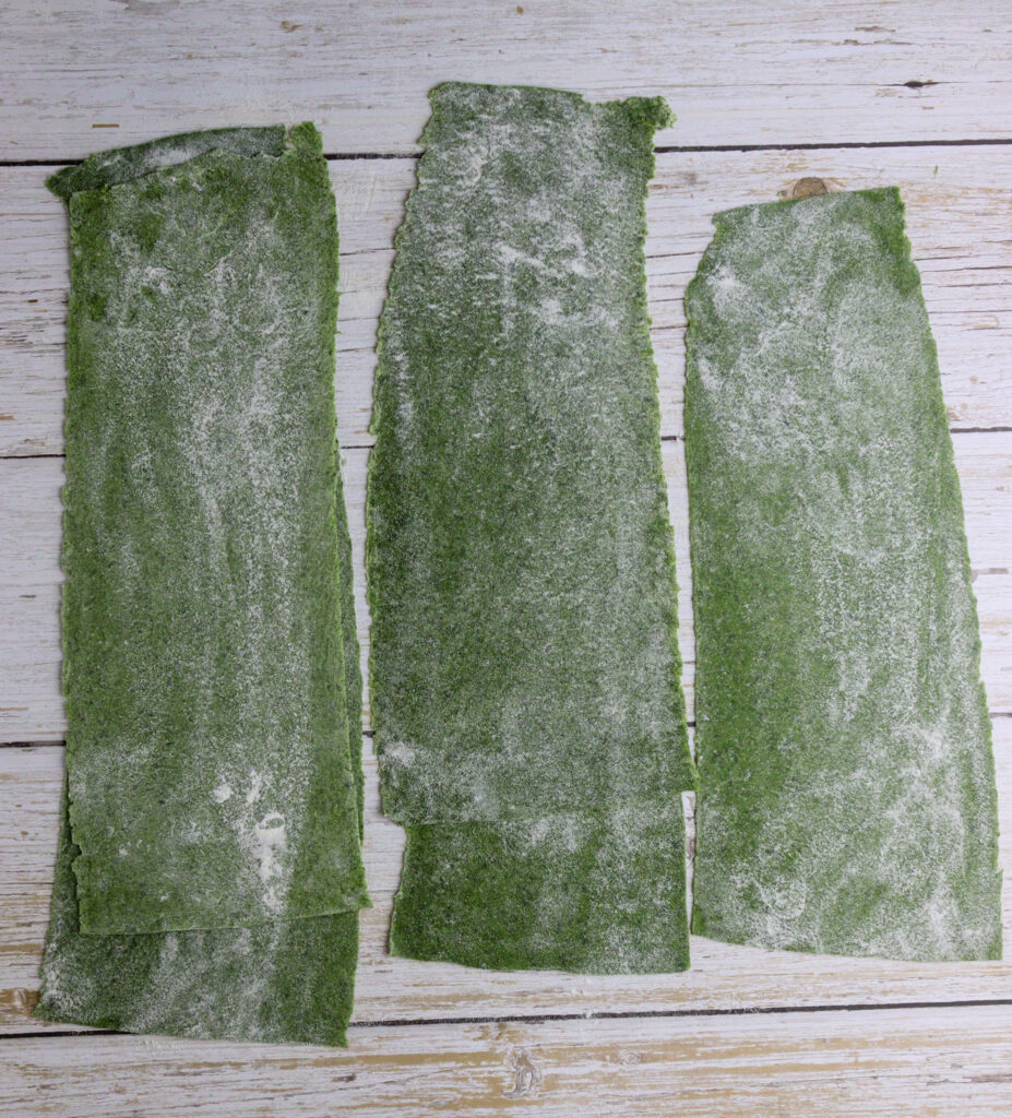 image showing how to sprinkle green pasta sheets with flour on both sides to prevent sticking together or sticking to the pasta maker 