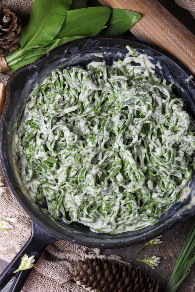 green pasta in a pan with a garlic sauce