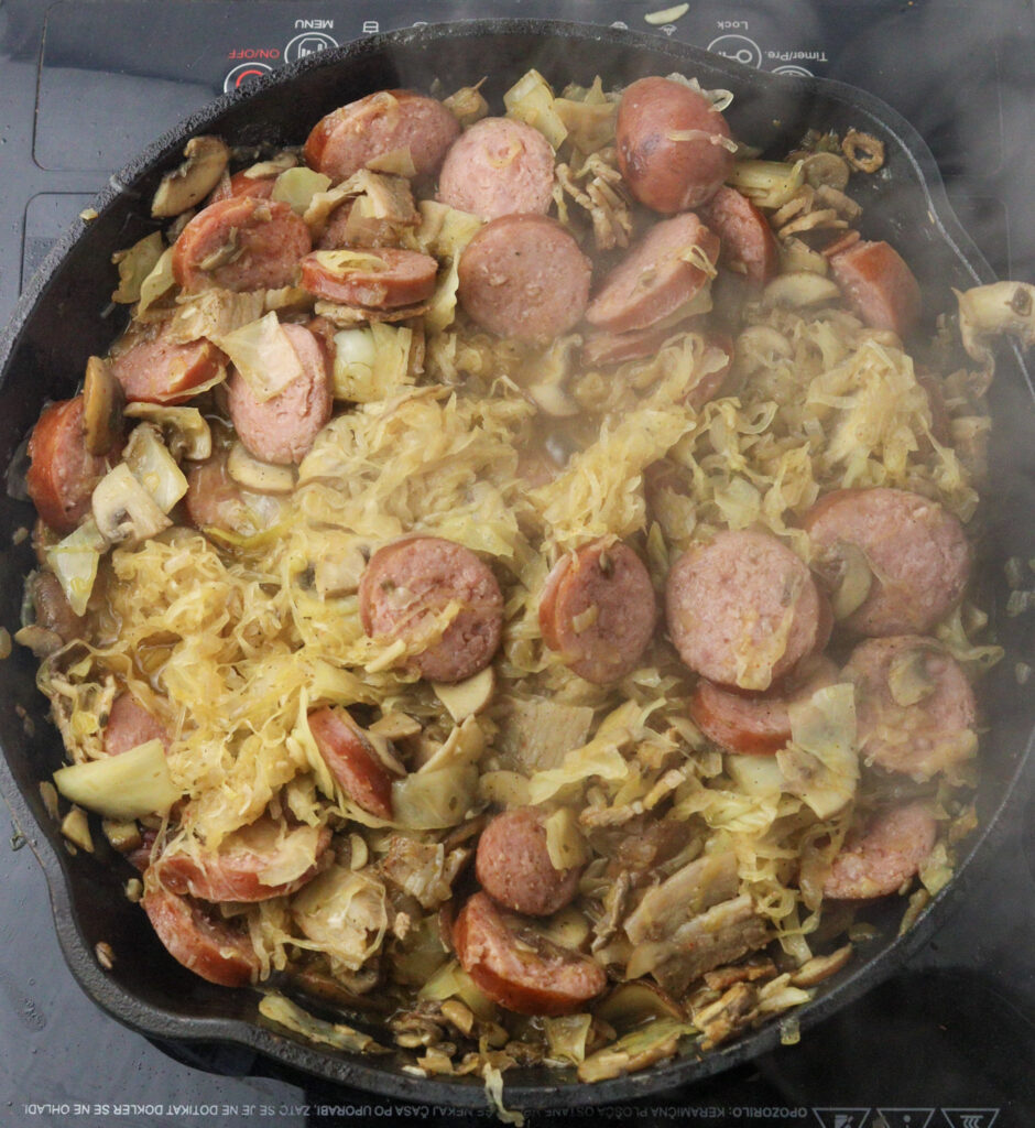 adding sauerkraut and smoked sausages to the pan 